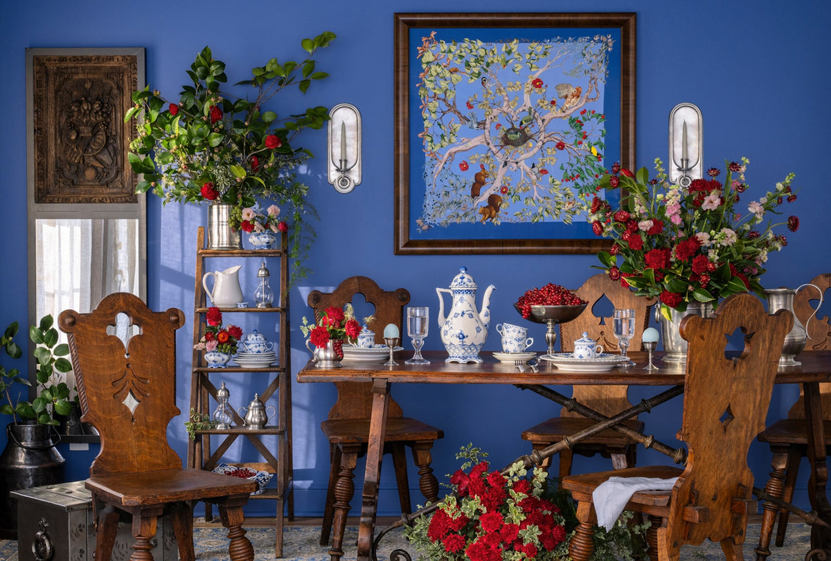 Dining room with wooden chairs, table, and decorative items against a blue wall.