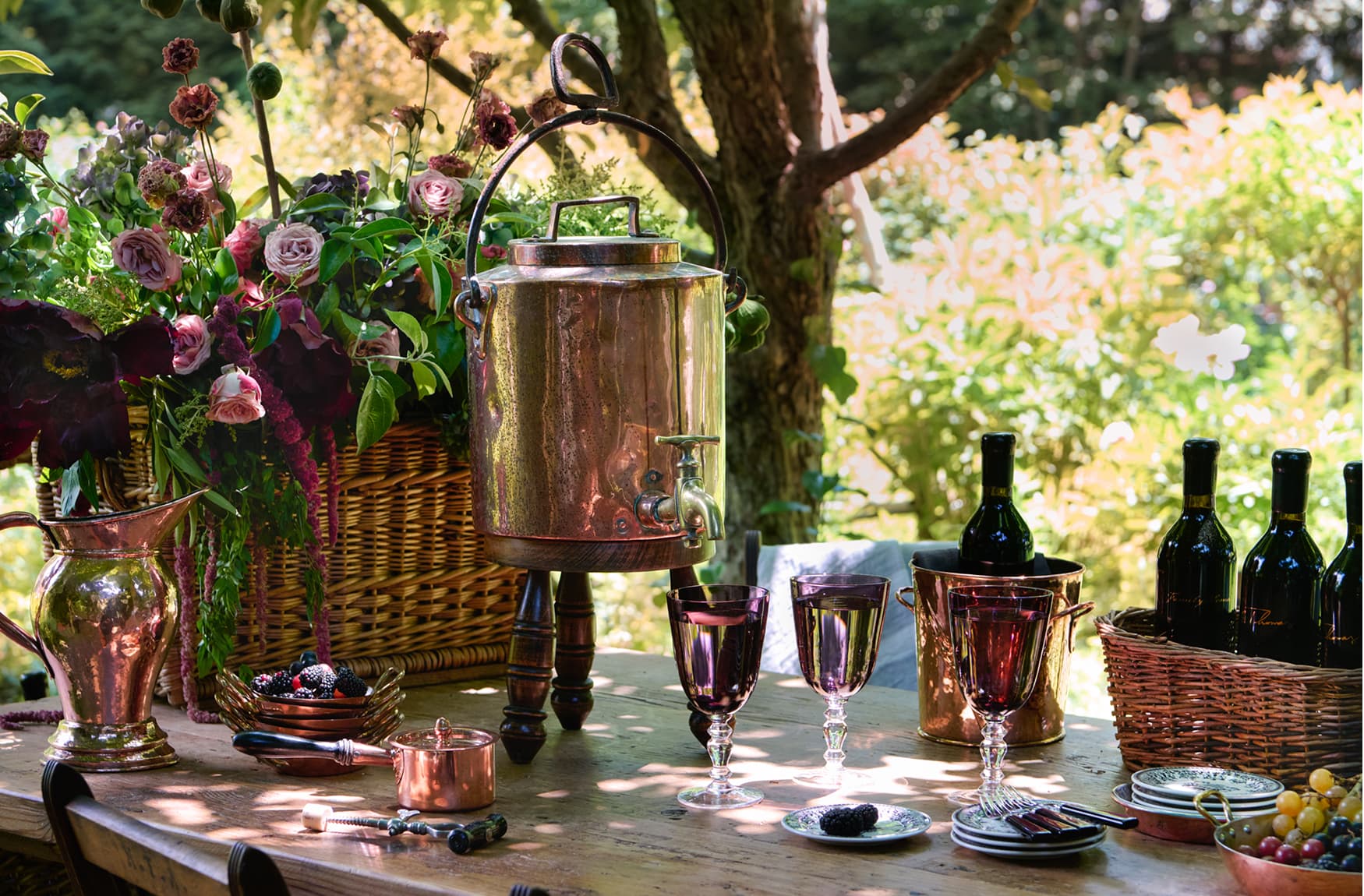 Outdoor setting with wine bottles, glasses, and decorative items on a table.