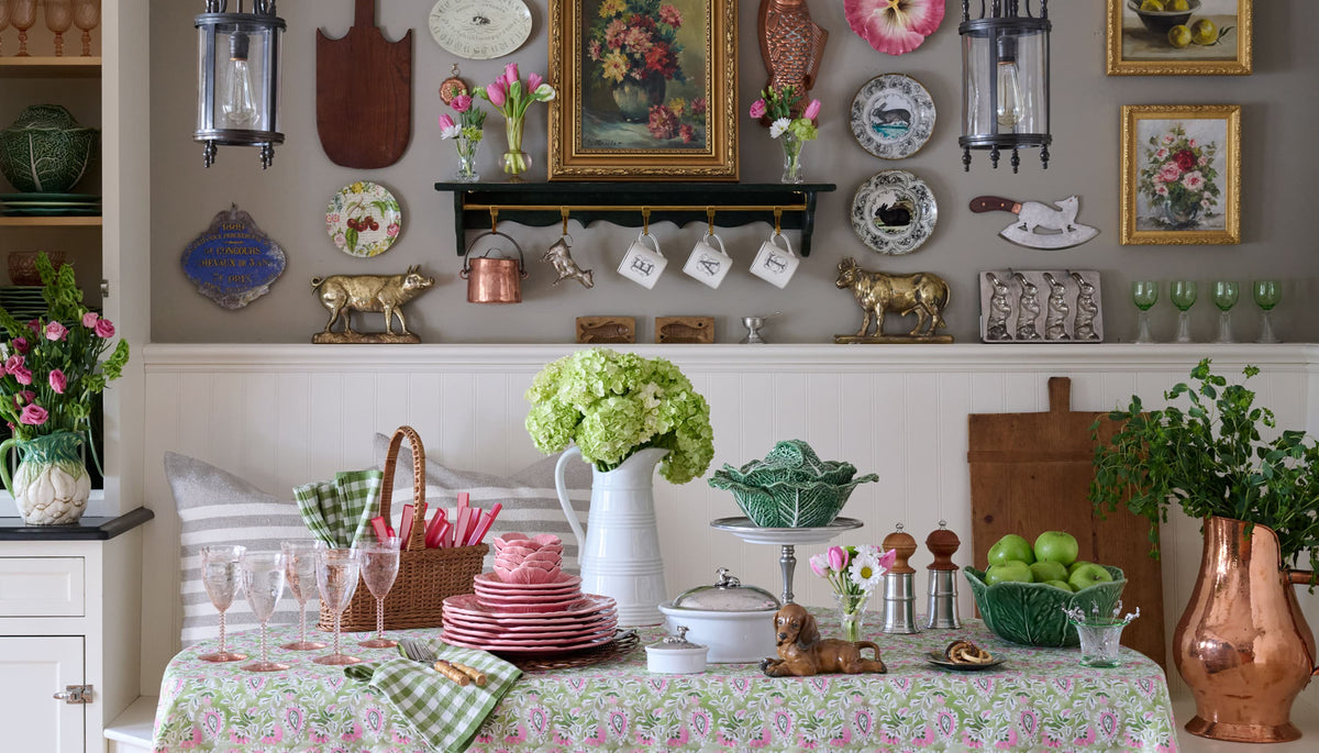 Kitchen with floral tablecloth, greenery, and various kitchenware.