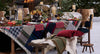 A rustic outdoor dining table set in a snowy setting, decorated with a patchwork quilt tablecloth, animal fur chairs, candles, and autumnal decorations. Weston Table.