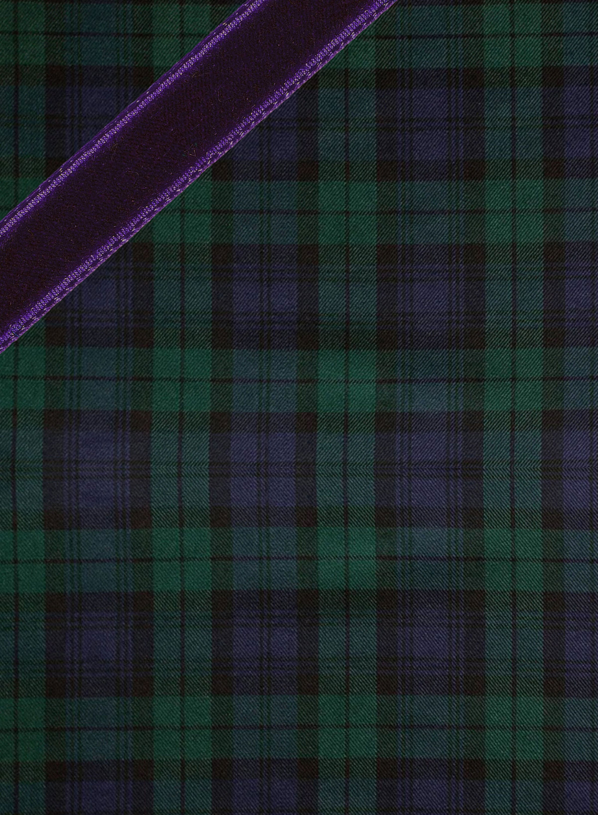 A close-up of a tartan plaid fabric pattern in dark green and deep blue, with a diagonal purple stripe running across the upper left corner. Weston Table.