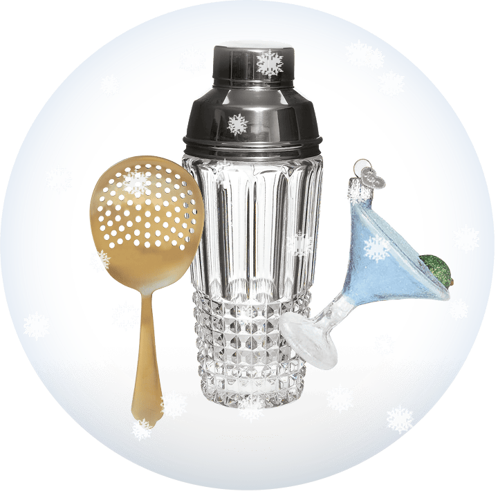 Cocktail shaker with gold cocktail strainer and martini glass Christmas ornament on a transparent background with snow.