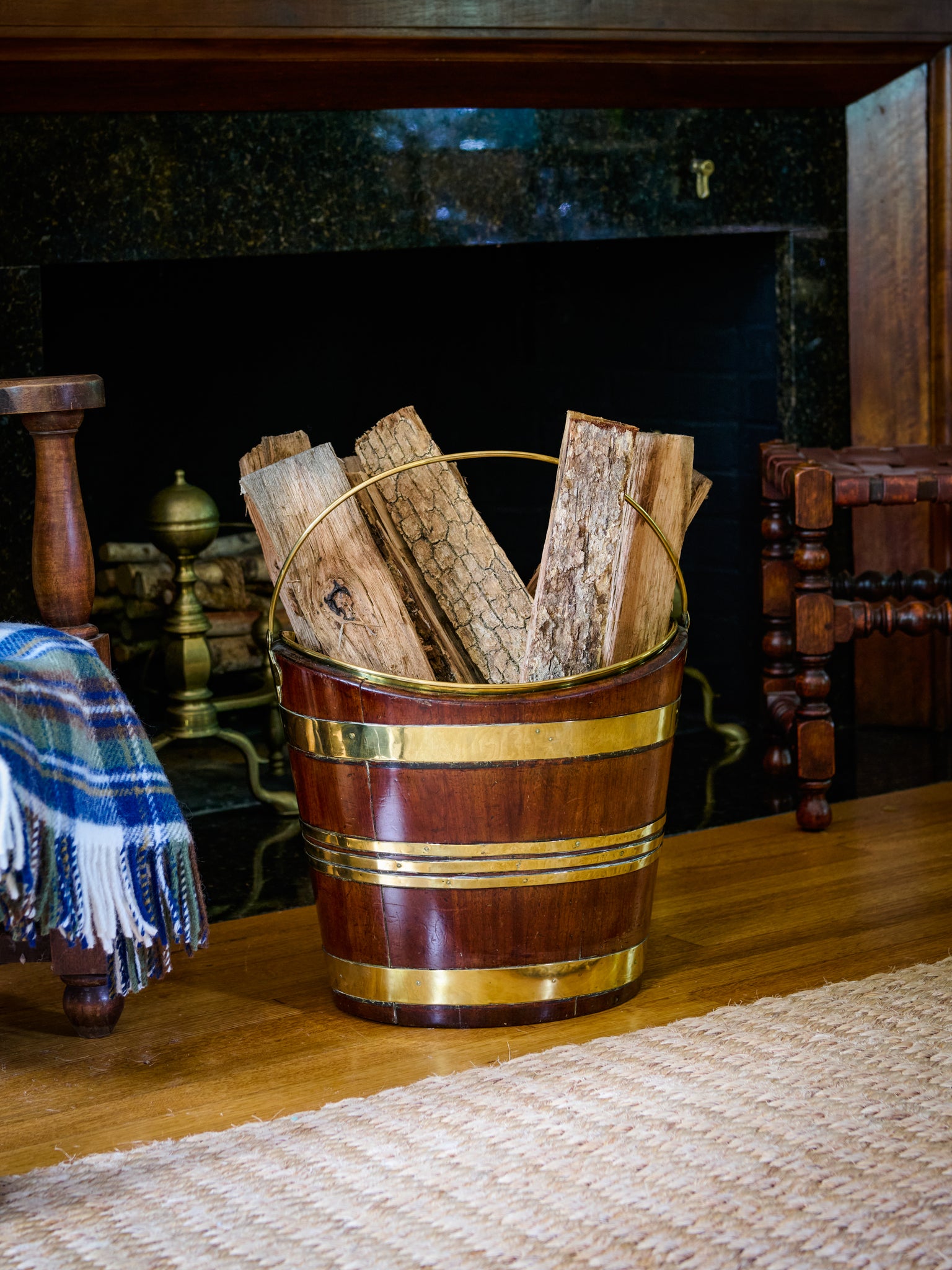 Wooden bucket filled with firewood in front of a fireplace.